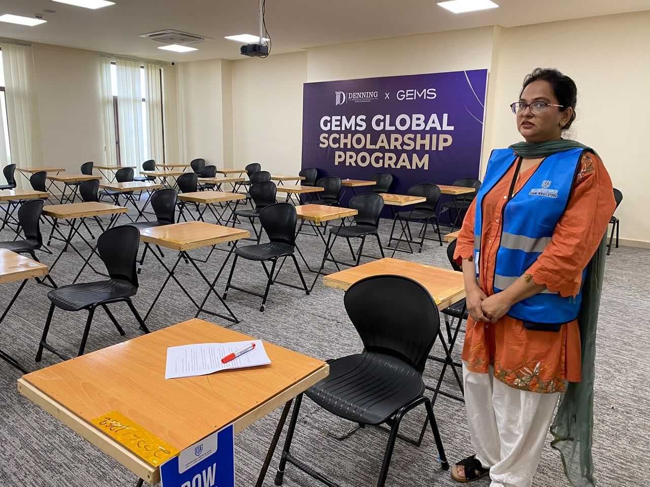 Invigilator standing in a prepared exam hall